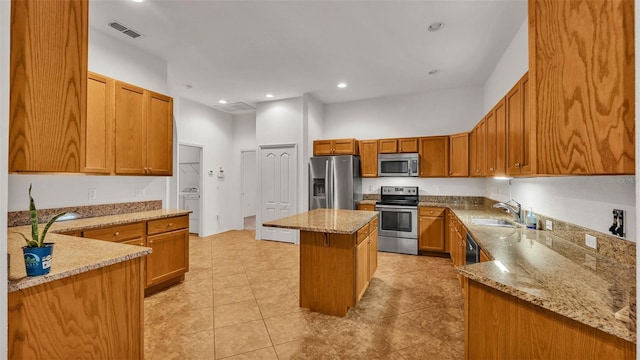 kitchen with a kitchen island, light stone counters, sink, and stainless steel appliances