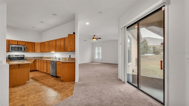 kitchen with ceiling fan, a towering ceiling, light carpet, sink, and stainless steel appliances