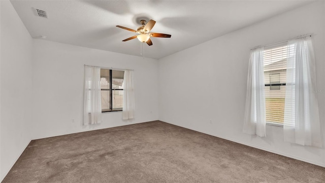 carpeted spare room with ceiling fan and a wealth of natural light