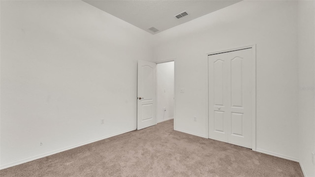 unfurnished bedroom featuring light colored carpet and a closet