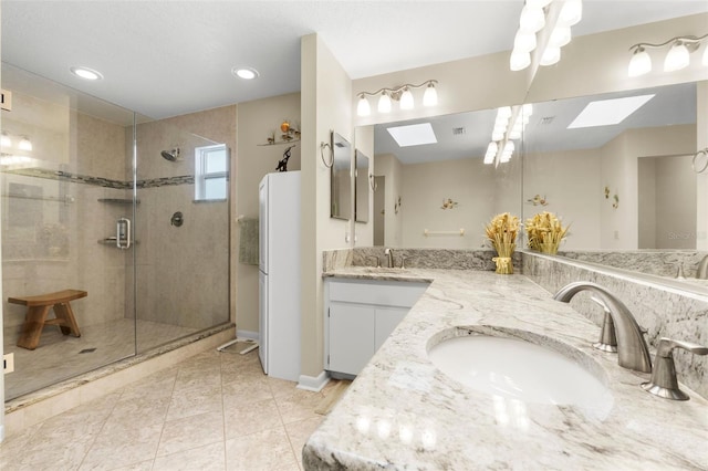 bathroom featuring vanity, a skylight, and a shower with shower door