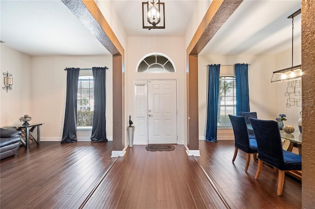 foyer with a healthy amount of sunlight, an inviting chandelier, and dark hardwood / wood-style flooring