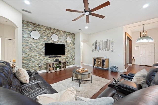 living room with ceiling fan with notable chandelier and dark hardwood / wood-style floors