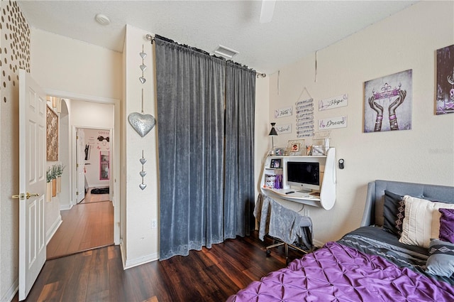 bedroom with ceiling fan, a textured ceiling, and dark hardwood / wood-style flooring