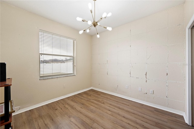 spare room featuring hardwood / wood-style floors and an inviting chandelier