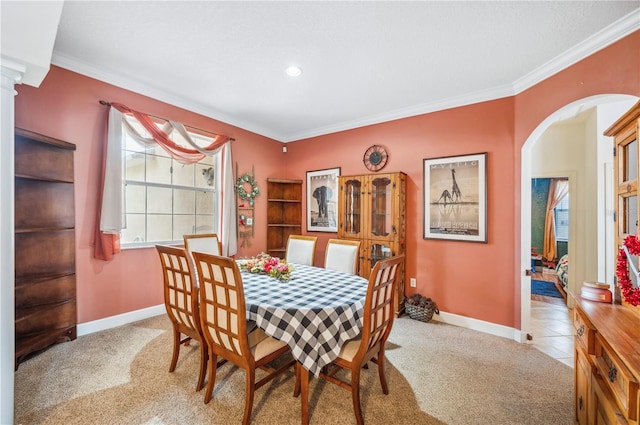 carpeted dining space featuring ornate columns and ornamental molding