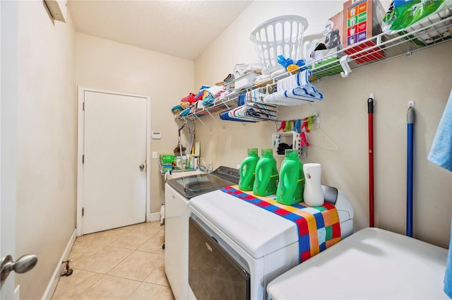 laundry room with light tile patterned flooring, a textured ceiling, and washer and clothes dryer