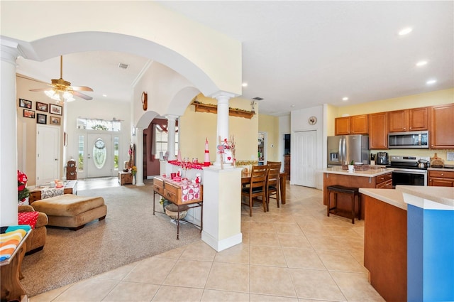 kitchen with a kitchen bar, decorative columns, a center island, and stainless steel appliances