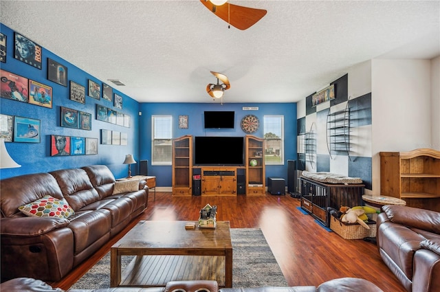 living room featuring ceiling fan, a textured ceiling, and dark hardwood / wood-style flooring