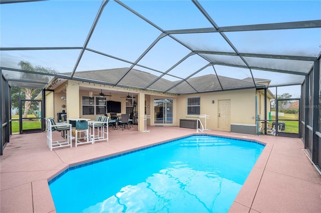 view of swimming pool with a patio, ceiling fan, and glass enclosure