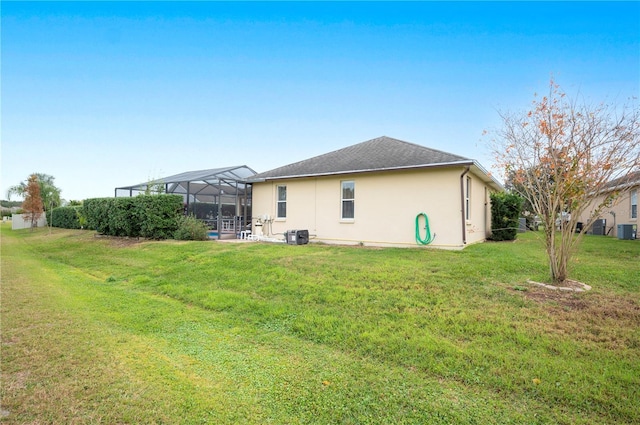 back of house featuring a lanai, a yard, and central air condition unit