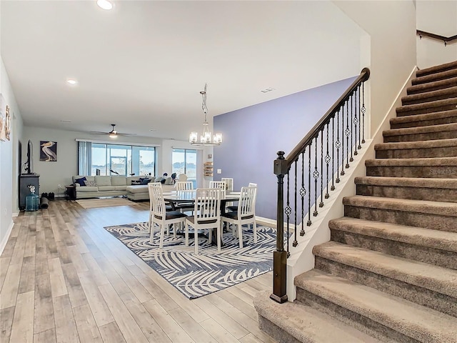 dining room featuring ceiling fan with notable chandelier and light hardwood / wood-style floors