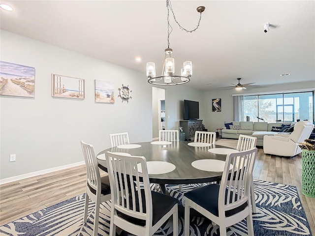 dining room with ceiling fan with notable chandelier and light hardwood / wood-style floors