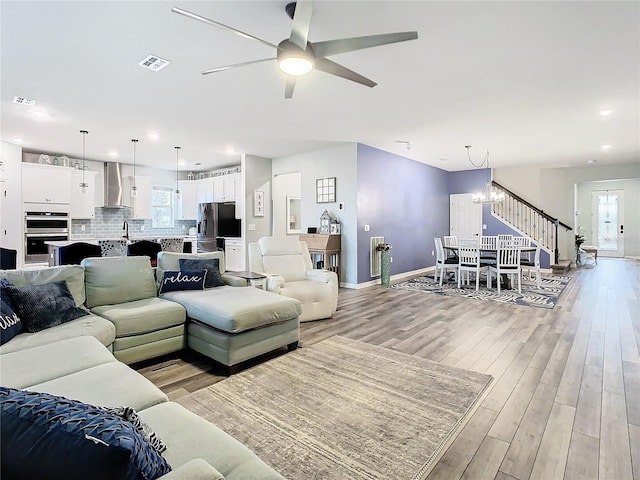 living room featuring sink, light hardwood / wood-style floors, and ceiling fan with notable chandelier