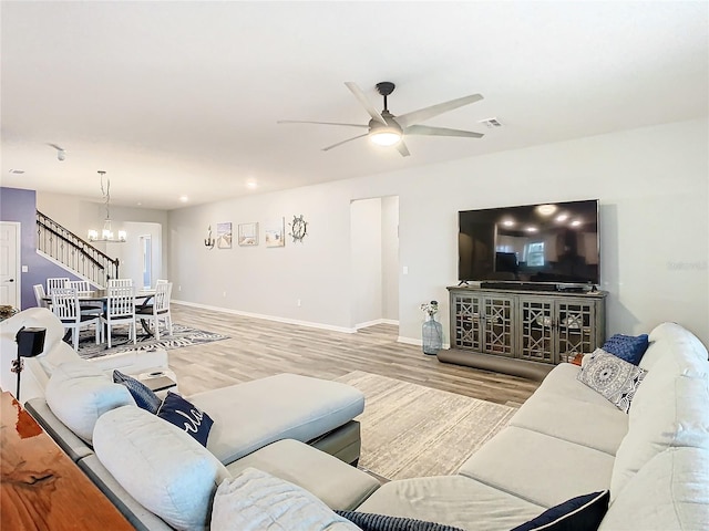 living room with hardwood / wood-style floors and ceiling fan with notable chandelier