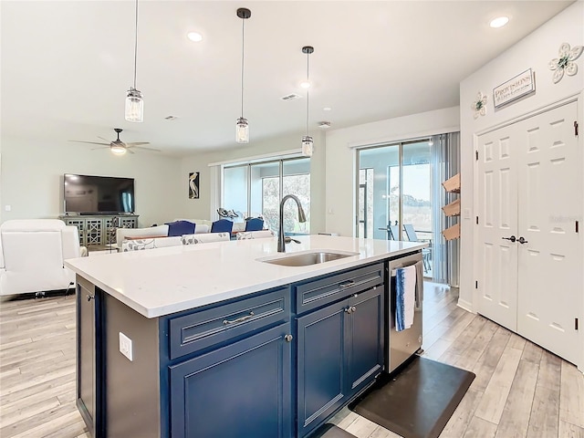 kitchen with stainless steel dishwasher, pendant lighting, sink, blue cabinets, and an island with sink