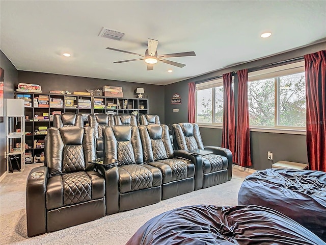 cinema room with ceiling fan and light colored carpet