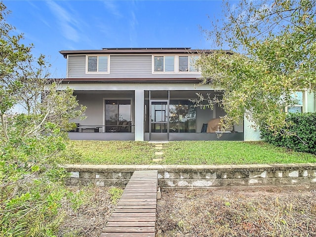 rear view of house with a sunroom and a lawn