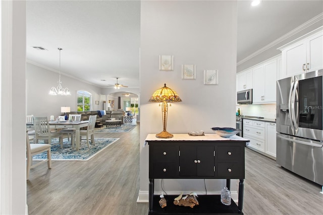 kitchen featuring ornamental molding, stainless steel appliances, light hardwood / wood-style flooring, and white cabinets