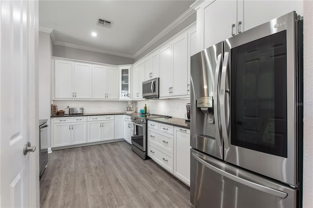 kitchen with ornamental molding, appliances with stainless steel finishes, light hardwood / wood-style flooring, and white cabinets