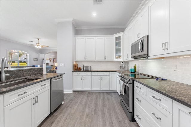 kitchen featuring white cabinetry, sink, dark stone counters, ornamental molding, and stainless steel appliances