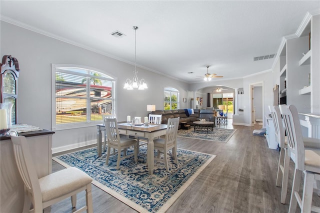 dining area with crown molding, dark hardwood / wood-style floors, and ceiling fan with notable chandelier