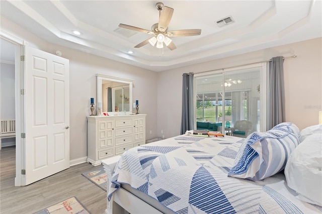 bedroom with ceiling fan, access to exterior, a raised ceiling, and light wood-type flooring