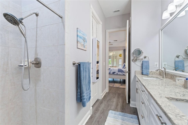 bathroom featuring hardwood / wood-style flooring, vanity, and a tile shower