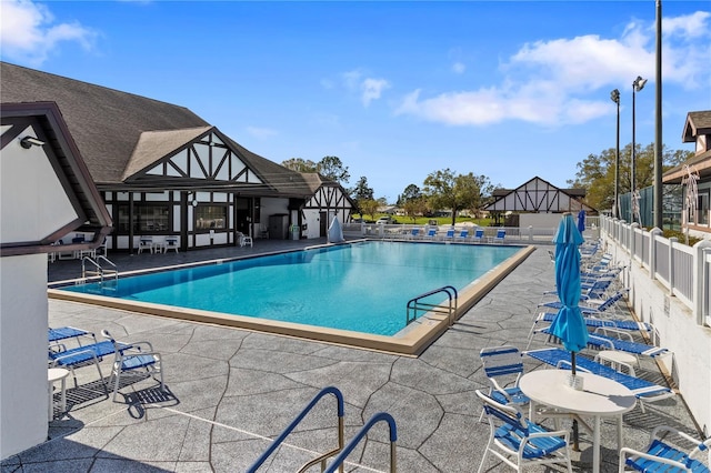 community pool with fence and a patio area