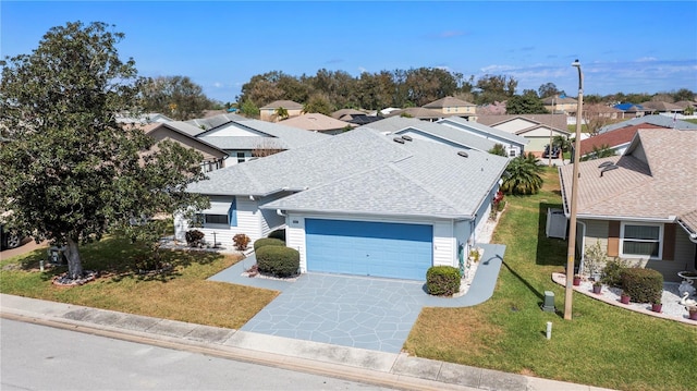 view of front of property with an attached garage, concrete driveway, a front lawn, roof with shingles, and a residential view