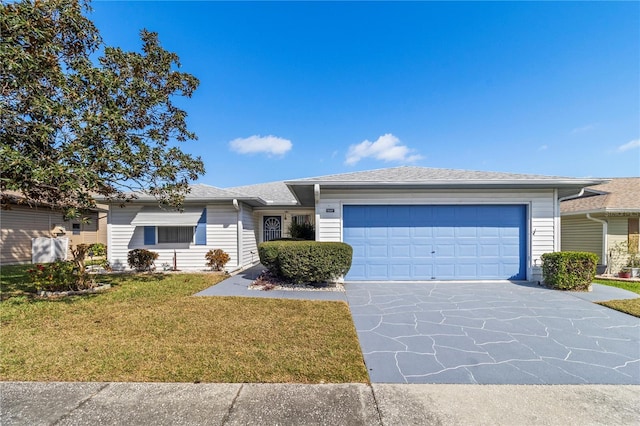 ranch-style home featuring a shingled roof, a garage, concrete driveway, and a front yard
