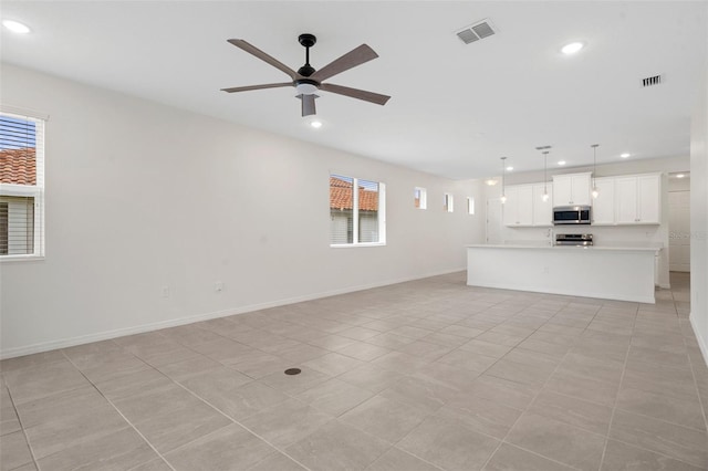 unfurnished living room with ceiling fan, light tile patterned floors, and plenty of natural light