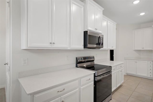 kitchen with stainless steel appliances, white cabinetry, and light tile patterned flooring