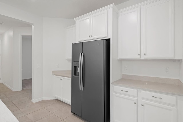 kitchen featuring light stone counters, light tile patterned floors, white cabinets, and stainless steel fridge with ice dispenser