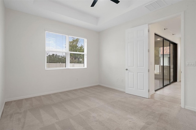 unfurnished room with light colored carpet, ceiling fan, and a raised ceiling