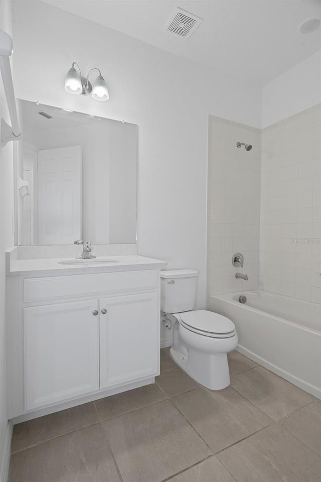 full bathroom with tile patterned floors, tiled shower / bath combo, vanity, and toilet