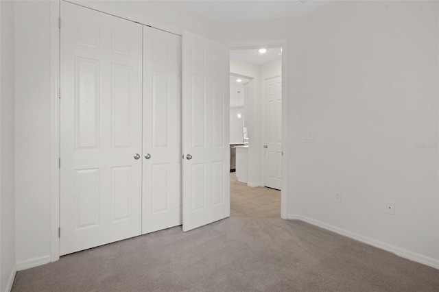 unfurnished bedroom with light colored carpet and a closet