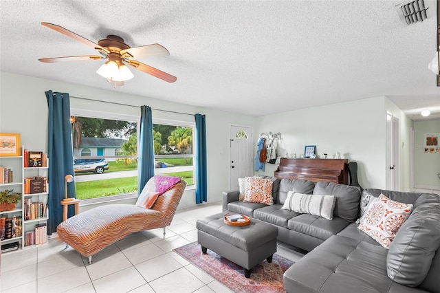 living room featuring a ceiling fan, visible vents, a textured ceiling, and light tile patterned floors