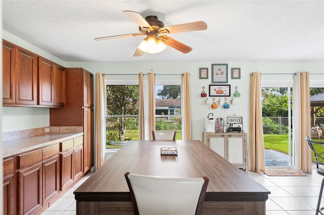 dining space featuring light tile patterned floors, ceiling fan, a textured ceiling, and plenty of natural light