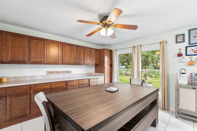 dining room with a textured ceiling, light tile patterned floors, and a ceiling fan