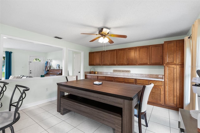 dining space with light tile patterned floors, ceiling fan, visible vents, and a textured ceiling