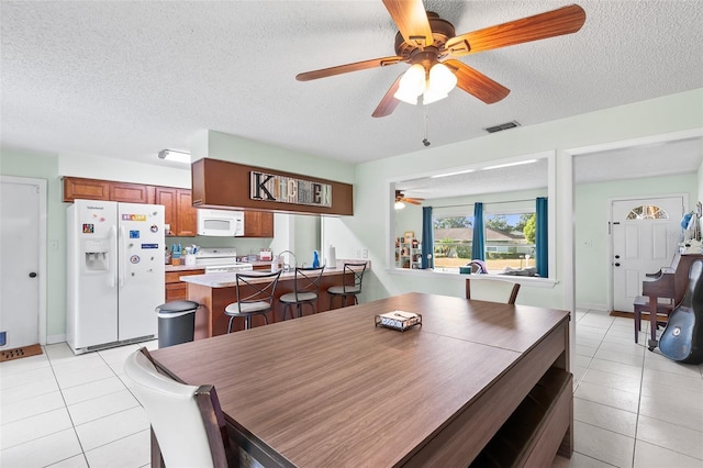 dining area featuring light tile patterned floors, visible vents, and a textured ceiling