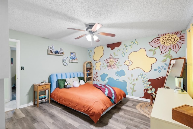 bedroom featuring a ceiling fan, a textured ceiling, baseboards, and wood finished floors