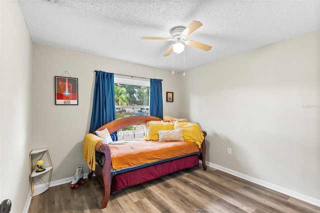 bedroom with ceiling fan, a textured ceiling, baseboards, and wood finished floors