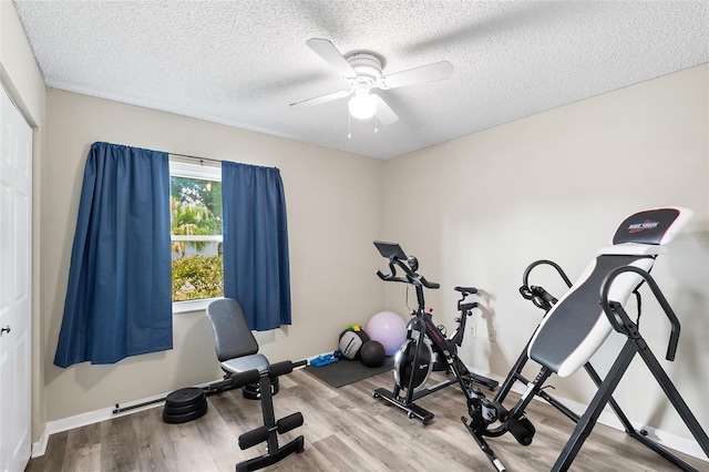 workout room featuring a textured ceiling, wood finished floors, a ceiling fan, and baseboards