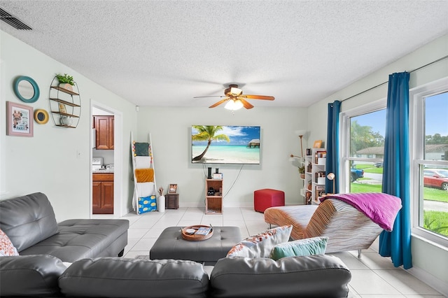 living area featuring light tile patterned floors, a textured ceiling, visible vents, and a ceiling fan