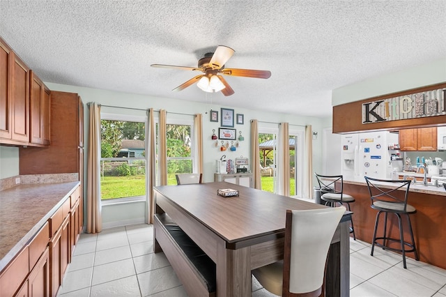 dining space with light tile patterned floors, a textured ceiling, a ceiling fan, and a wealth of natural light