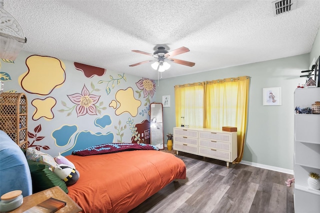 bedroom featuring baseboards, visible vents, ceiling fan, wood finished floors, and a textured ceiling