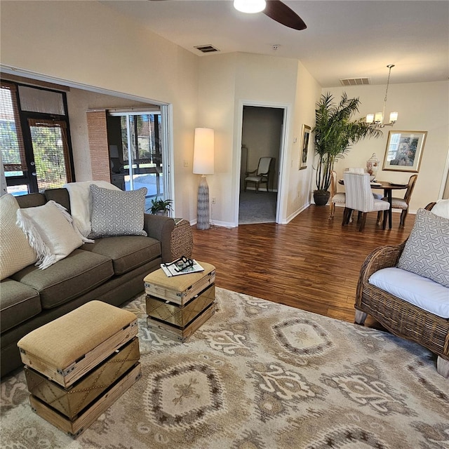 living room with baseboards, visible vents, wood finished floors, and ceiling fan with notable chandelier