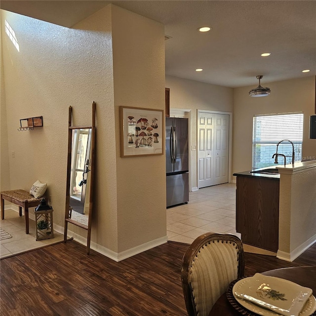 kitchen with light wood-type flooring, a sink, freestanding refrigerator, and recessed lighting